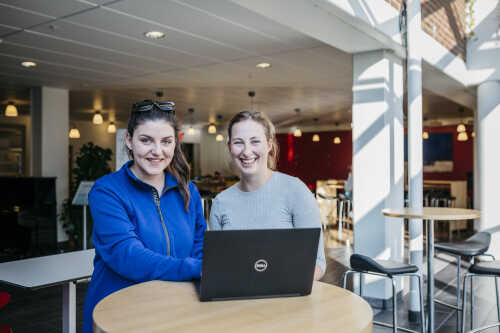 To kvinnelige studenter foran en laptop på campus 