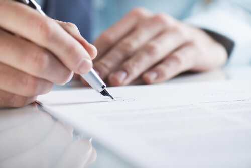 En person som signerer papirer med en penn