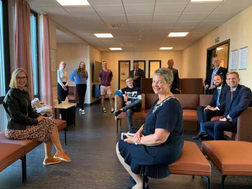 Bilde et tatt inne i et av felles arealene, flere sitter sammen og ser smilende ut. 