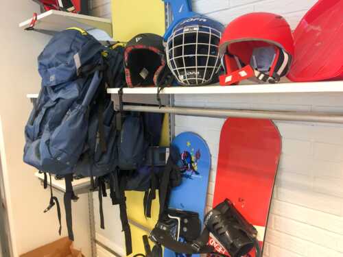 Picture of bags, helmets and a blue and read snowboards.