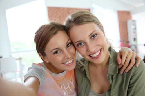 To jenter som smiler og tar et bilde av seg selv sammen