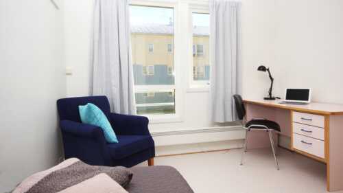 Furnished room at Flatvold with bed, armchair and desk