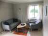 Nice living room furnished with two gray sofas, a small table and bright curtains