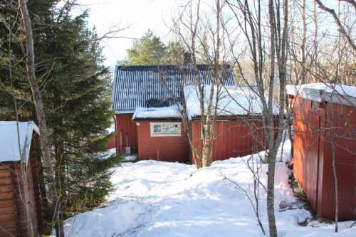 The cabin is red, the picture was taken in the winter so there is snow around. The cabin is located 