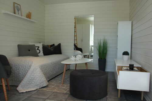  The bedroom is bright and furnished with a bed, table, pouf and shelf