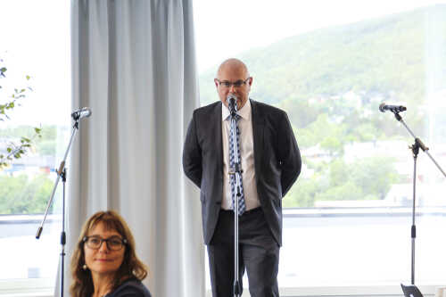 Bilder fra en av talerne på åpningen ikledd mørk går dress. 