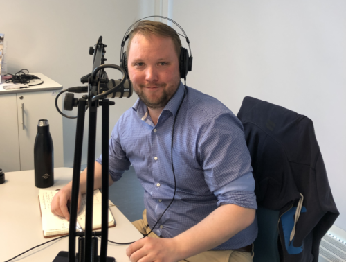 Studentvert og podcastvert Øystein Strømsnes, han sitter i studio med øreklokker på hodet og mik