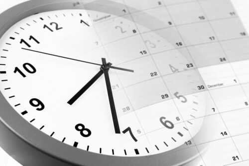 Hvit klokke med sorte visere og en kalender 