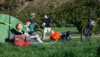 Five students on a trip with bicycles and tent. They are enjoying a break in the sun.   