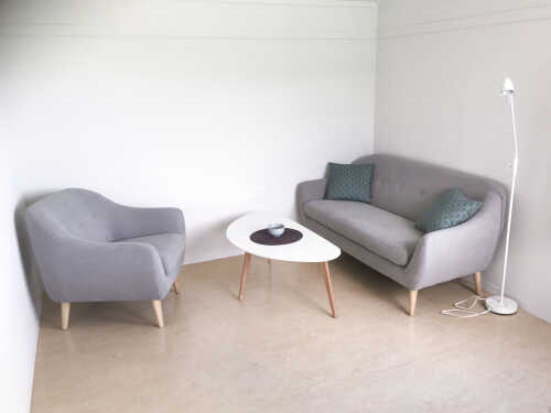 Bilde fra en et lyst oppholdsrom med lyse grå møbler. 