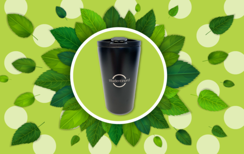 The thermo cup is black with a silver Studentinord logo in the middle. It is located inside a green 